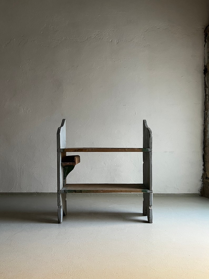 May include: A rustic wooden shelf unit with two shelves and a small side shelf. The shelf is painted white with green accents and has a distressed look.