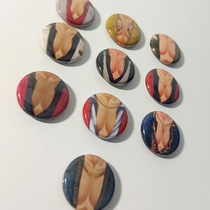 May include: Twelve round button pins with different images of a person's torso. The images feature different clothing styles and colors, including red, blue, yellow, and black.