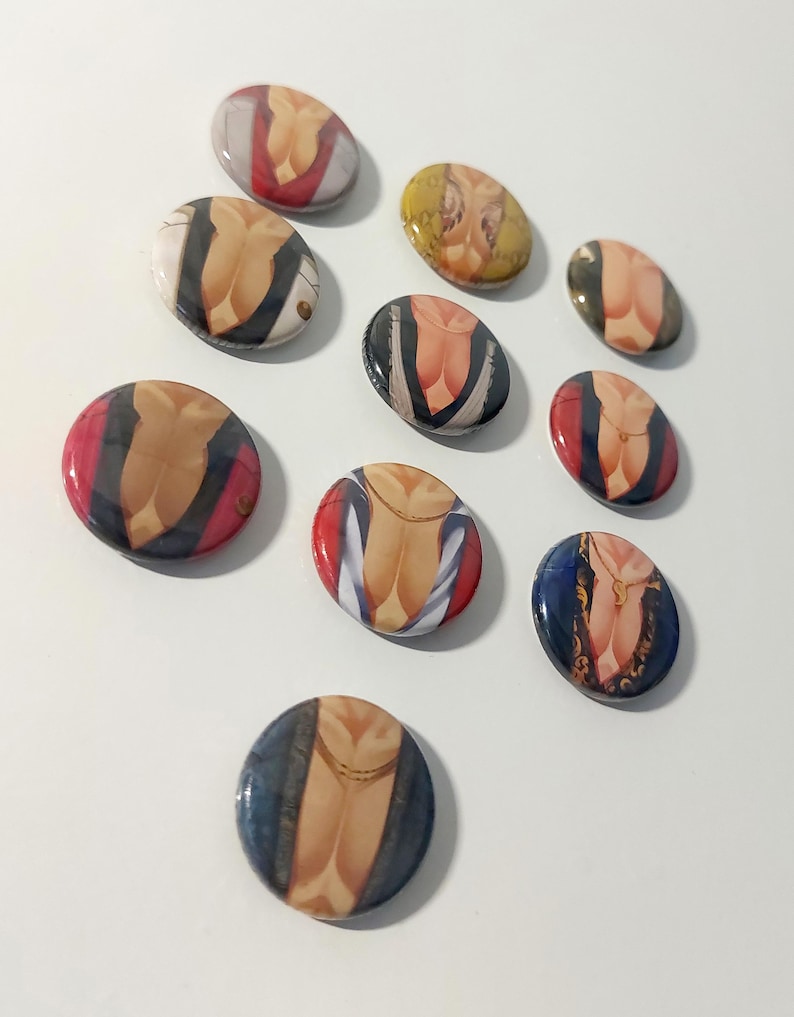 May include: Twelve round button pins with different images of a person's torso. The images feature different clothing styles and colors, including red, blue, yellow, and black.