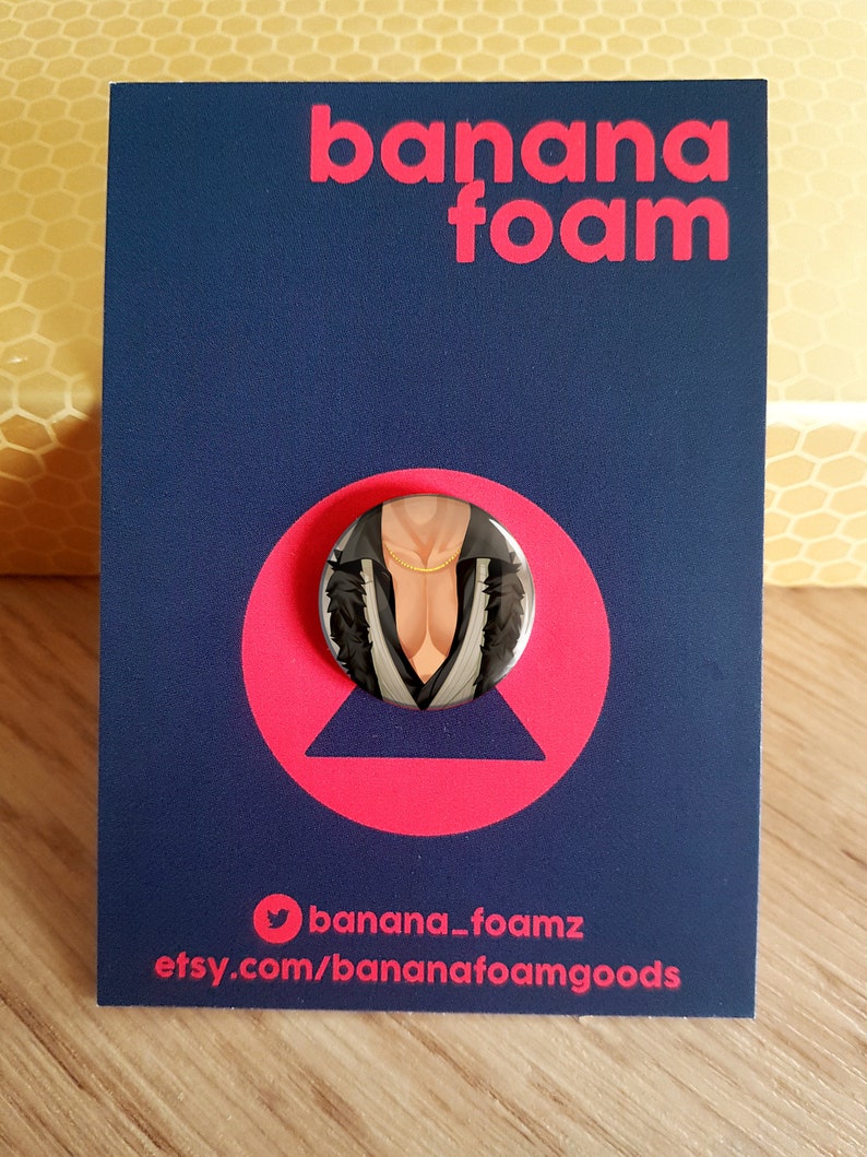 May include: A black and white button featuring a person wearing a black and white jacket with a gold chain necklace. The button is on a blue background with the text "banana foam" in pink letters. The text "banana_foamz" and "etsy.com/bananafoamgoods" are also visible.