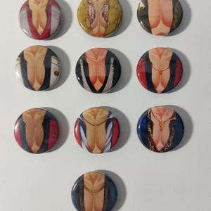 May include: Ten round button pins featuring a stylized image of a person's torso with different clothing and jewelry designs. The designs include a red jacket, a yellow patterned shirt, a blue shirt with a white collar, and a gold chain necklace.