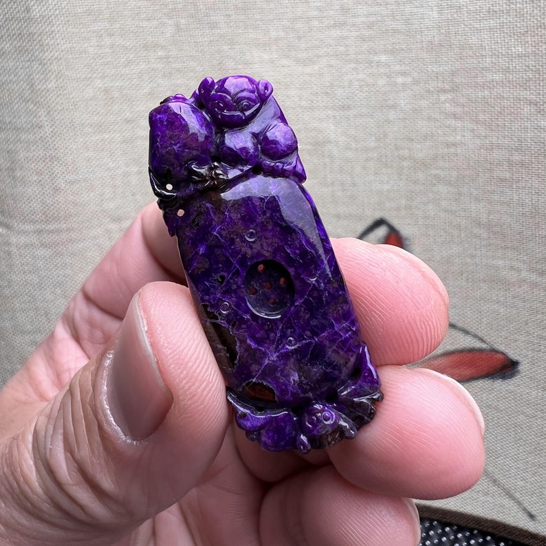 May include: Purple jade pendant carved with a mythical creature. The pendant has a detailed design and a smooth, polished finish.