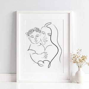May include: A framed black and white line art print. The artwork depicts a mother holding a child, both faces are visible. The child wears a floral crown. The art is in a white frame, and a vase of flowers is in the background.