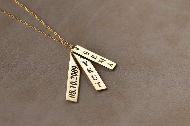 May include: Gold necklace with three rectangular pendants. The pendants are engraved with the names "SEMA", "AYKUT", and the date "08.10.2009".