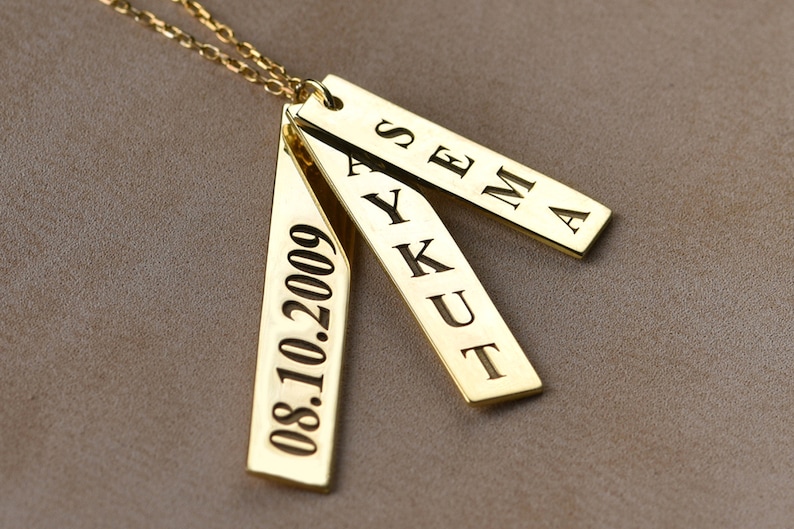 May include: Gold necklace with three rectangular pendants. The pendants are engraved with the names "SEMA", "AYKUT", and the date "08.10.2009".