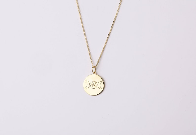 May include: A gold necklace with a round pendant featuring a triple moon and pentacle design.