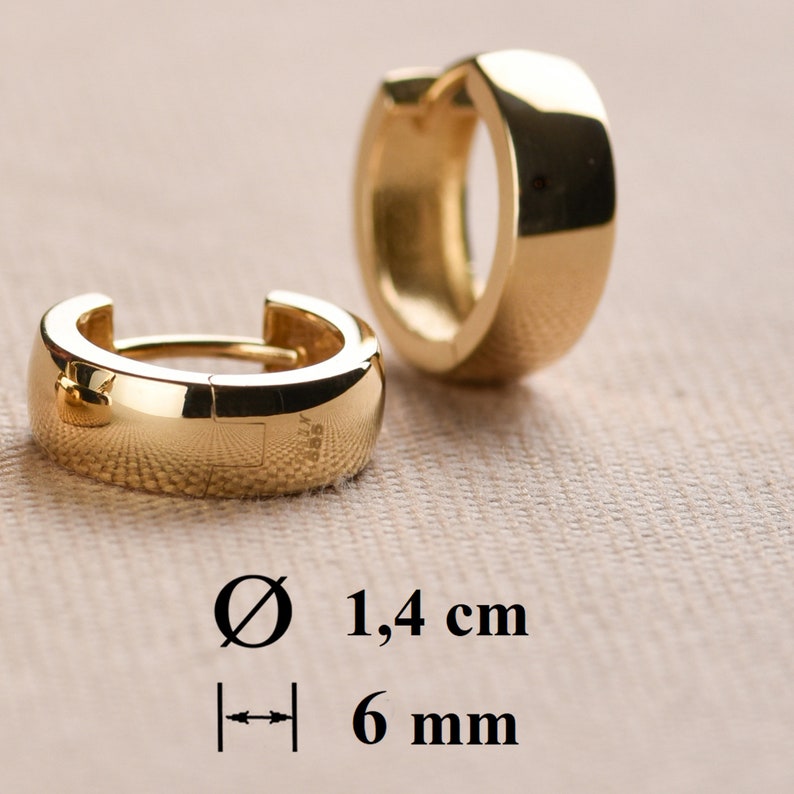 May include: A pair of gold hoop earrings with a diameter of 1.4 cm and a width of 6 mm.