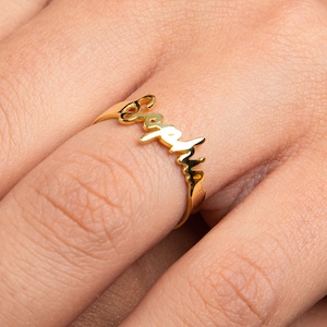 May include: A gold-colored ring with the name "Sarah" written in cursive script.