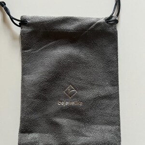 May include: A gray velvet drawstring pouch with a silver logo that reads "bejeweled".