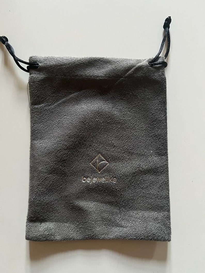 May include: A gray velvet drawstring pouch with a silver logo that reads "bejeweled".
