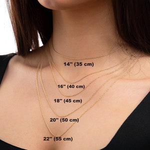 May include: Five gold chains of different lengths, laid out on a person's neck, showing the lengths in inches and centimeters. The lengths are 14 inches (35 cm), 16 inches (40 cm), 18 inches (45 cm), 20 inches (50 cm), and 22 inches (55 cm).