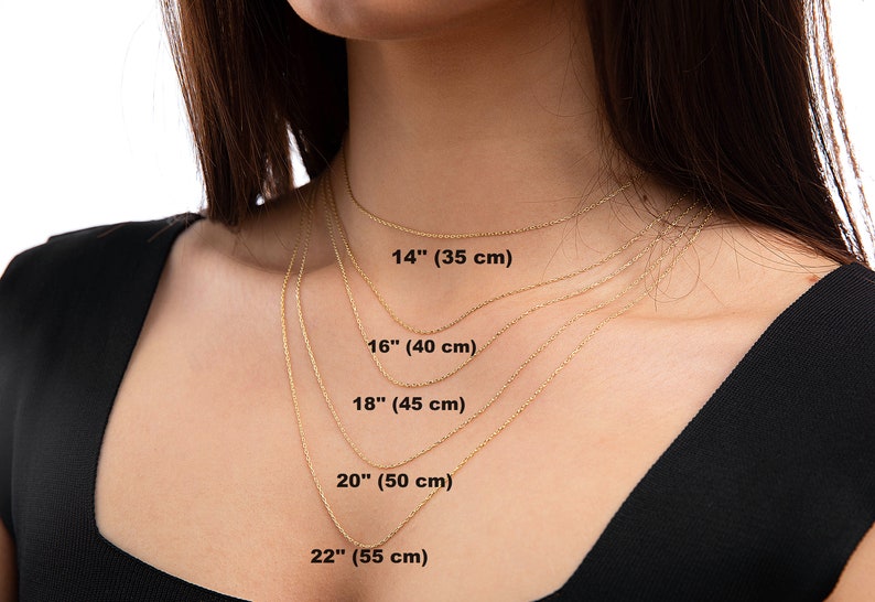 May include: Five gold chains of different lengths, laid out on a person's neck, showing the lengths in inches and centimeters. The lengths are 14 inches (35 cm), 16 inches (40 cm), 18 inches (45 cm), 20 inches (50 cm), and 22 inches (55 cm).