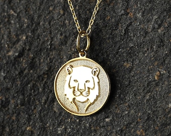 May include: A gold chain necklace with a round pendant featuring a white silhouette of a lion's head.