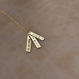 May include: Gold necklace with three rectangular pendants. The pendants are engraved with the names "Sena", "Ykut", and the date "08.10.2009".