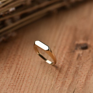 May include: A gold signet ring with a flat, rectangular top.