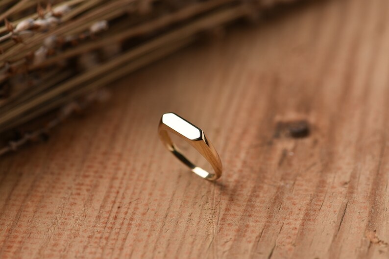 May include: A gold signet ring with a flat, rectangular top.