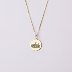 May include: A gold chain necklace with a round pendant featuring a crown design with small clear stones.