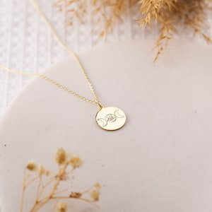 May include: Gold necklace with a round pendant featuring a triple moon and pentacle design.
