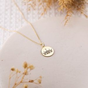 May include: A gold chain necklace with a round pendant featuring a crown design. The crown is made of small, sparkling stones.