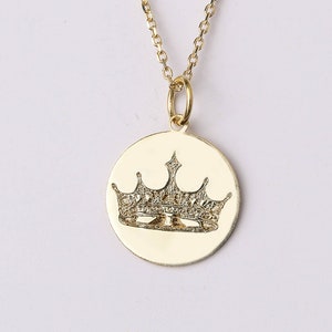 May include: A gold pendant necklace with a round charm featuring a detailed crown design with small diamonds.