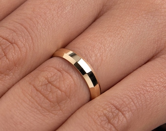 May include: A simple gold wedding band with a slightly beveled edge.