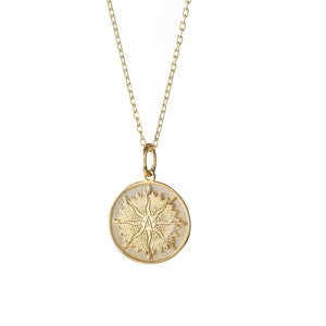 May include: A gold necklace with a round pendant featuring a detailed sun design.