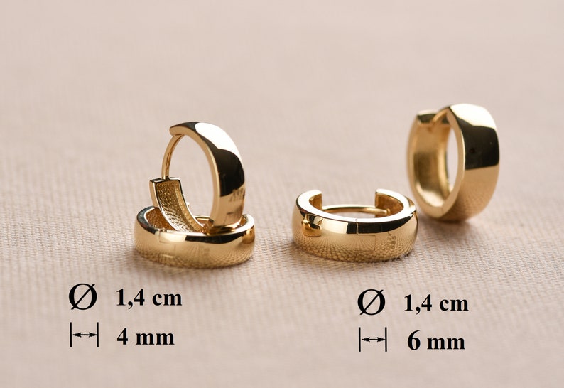 May include: Two pairs of gold hoop earrings. The earrings are 1.4 cm in diameter and have a width of 4 mm and 6 mm.