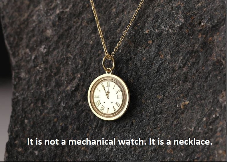 May include: A gold necklace with a round clock face pendant. The clock face has Roman numerals and a white background.