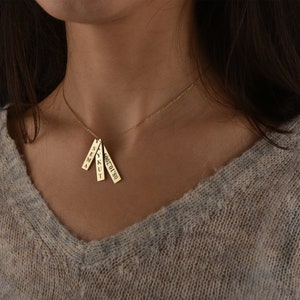 May include: A gold necklace with four small rectangular pendants, each with a name engraved on it. The names are "SEMA", "YKUT", "ALICE", and "OCT 19 90".