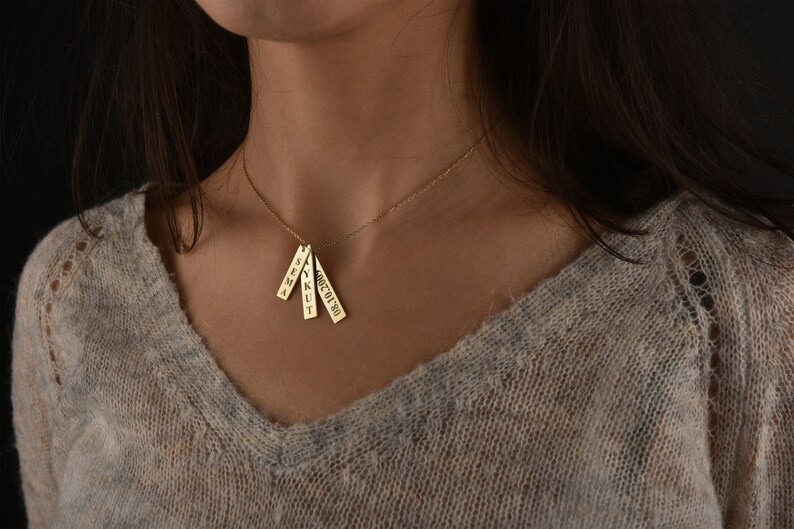 May include: A gold necklace with four small rectangular pendants, each with a name engraved on it. The names are "SEMA", "YKUT", "ALICE", and "OCT 19 90".