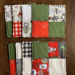 May include: Set of eight green, red, and white fabric coasters with a patchwork design featuring Christmas-themed patterns. The coasters are made of cotton fabric and are perfect for protecting surfaces from heat and spills.