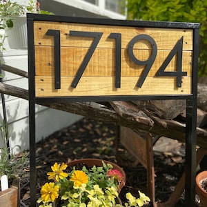 May include: Black metal house number sign with the number 17194 on a wooden background.