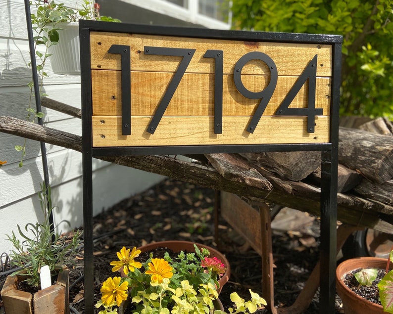 May include: Black metal house number sign with the number 17194 on a wooden background.