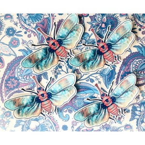 May include: Four stickers with a colourful insect design. The insects have large, patterned wings in shades of blue, green, and brown, with a pinkish-red body and long antennae. The stickers are set against a paisley patterned background.