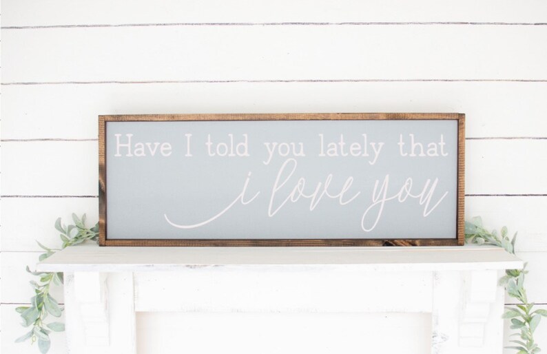 May include: A gray wooden sign with a brown frame, featuring the text "Have I told you lately that I love you" in white cursive lettering.