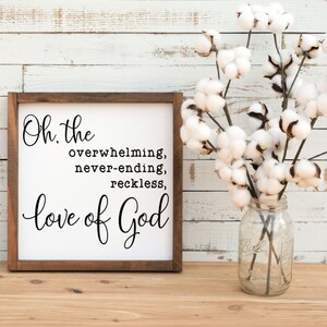 May include: A wooden sign with a white background and black text that reads "Oh, the overwhelming, never-ending, reckless, love of God".
