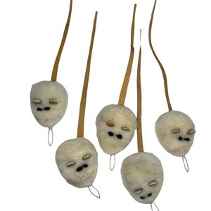 Pode incluir: Cinco enfeites de feltro branco em forma de rosto com olhos de feltro marrom e bocas de feltro preto pendurados em cordas marrons.