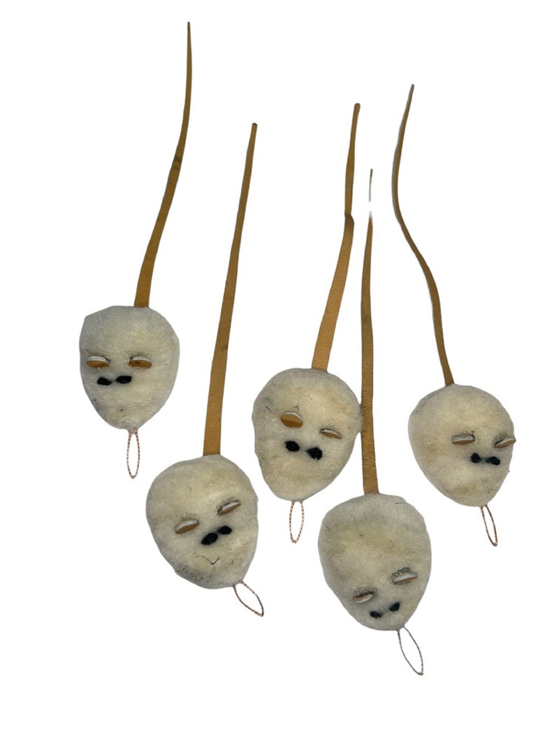 Pode incluir: Cinco enfeites de feltro branco em forma de rosto com olhos de feltro marrom e bocas de feltro preto pendurados em cordas marrons.