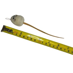 Pode incluir: Um brinquedo de rato de feltro branco com uma cauda de madeira marrom, medido com uma fita m&eacute;trica amarela. O rato mede aproximadamente 25 cm de comprimento.