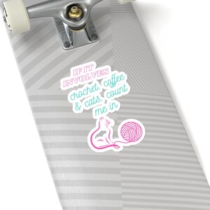 May include: A pink and blue sticker on a skateboard with the text "If it involves crochet, coffee & cats, count me in". A pink cat and a ball of yarn are illustrated below the text.