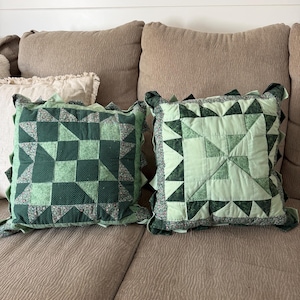 May include: Two square throw pillows featuring patchwork quilt designs in various shades of green. The left pillow displays a dark green geometric pattern, while the right pillow features a lighter green design with ruffled fabric edges.