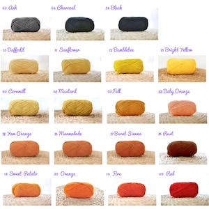 May include: A collection of yarn balls in various colours, including white, cream, rain, silver, ash, charcoal, black, daffodil, sunflower, bumblebee, bright yellow, cornmill, mustard, fall, baby orange, yam orange, marmalade, burnt sienna, rust, sweet potato, orange, fire, red, light rome red, dark rome red, ruby, and holly berry.