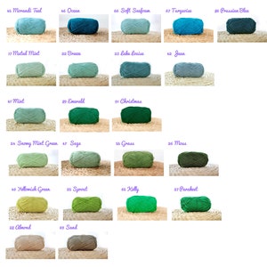 May include: A collection of yarn skeins in various shades of blue, green, and brown. The yarn is arranged in rows, with each skein labelled with a number and a colour name.