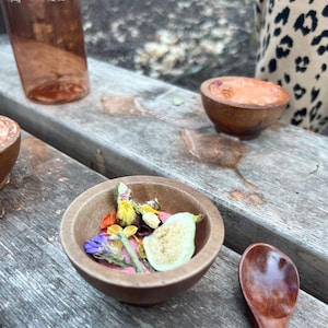 Puede incluir: Un cuenco de madera lleno de flores secas, frutas y semillas. El cuenco est&aacute; sobre una mesa de madera con una cuchara al lado.