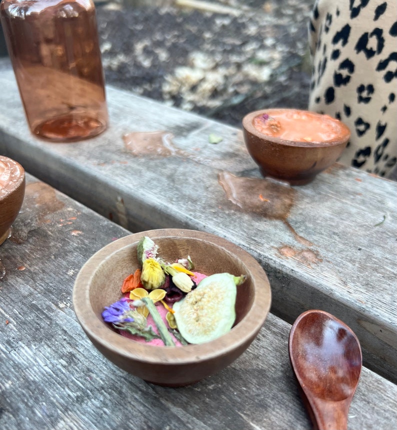 Puede incluir: Un cuenco de madera lleno de flores secas, frutas y semillas. El cuenco est&aacute; sobre una mesa de madera con una cuchara al lado.