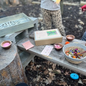 Puede incluir: Una bandeja de madera con un dise&ntilde;o tallado se encuentra sobre bloques de hormig&oacute;n. Una caja marr&oacute;n con el texto "Flower Herb" est&aacute; sobre una mesa de madera con un peque&ntilde;o cuenco de polvo rosa, un peque&ntilde;o cuenco de flores secas, un cuenco m&aacute;s grande de flores y hierbas secas, una peque&ntilde;a cuchara y una botella de vidrio con un tap&oacute;n de corcho.