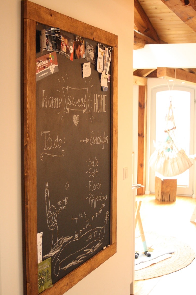 May include: A wooden framed chalkboard with the words "home sweet home" written in white chalk. The chalkboard also has a list of items to buy written in white chalk, including "salt", "juice", "meat", and "pepperoni".