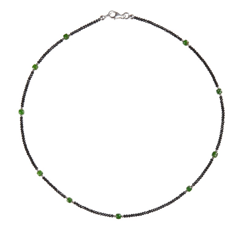 May include: A black beaded necklace with green gemstone accents.