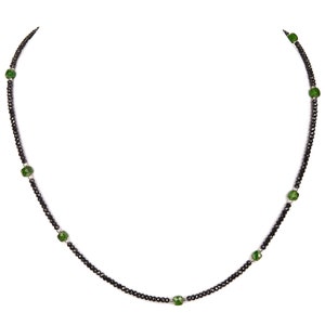 May include: A black beaded necklace with green gemstone accents.