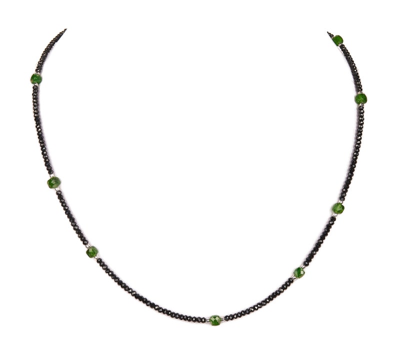 May include: A black beaded necklace with green gemstone accents.